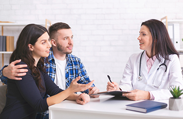 Cheerful doctor talking with millennial family about health care