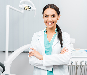 beautiful dentist standing with crossed arms in dental clinic